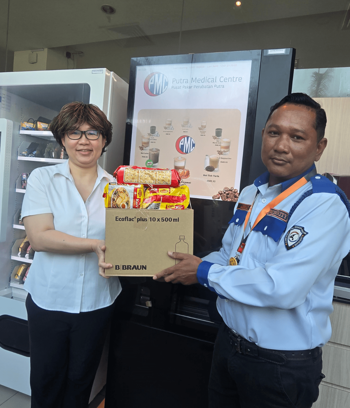 Photo 1 - Lee Geik Peng, Director of Allied Health Services of Putra Medical Centre, hands a care package to a member of the security force of the hospital.