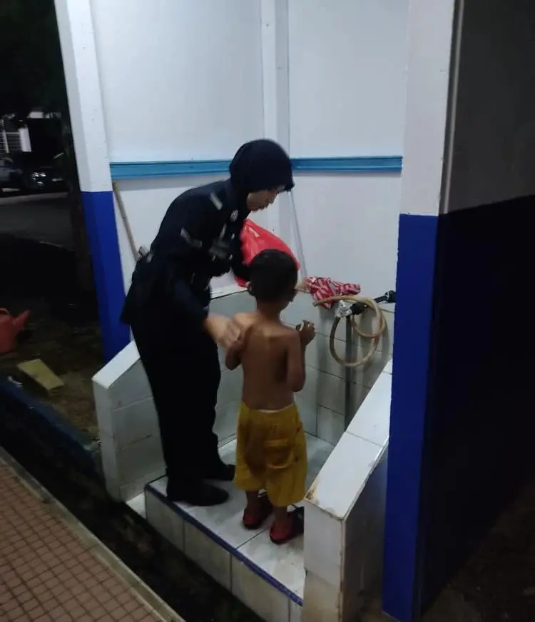 Lance Corporal Siti Sarah Ariffin giving prisoner's son a shower