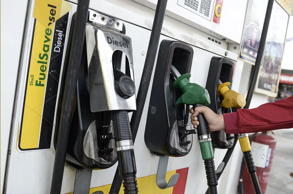 Woman using a pump nozzle at petrol station in M'sia