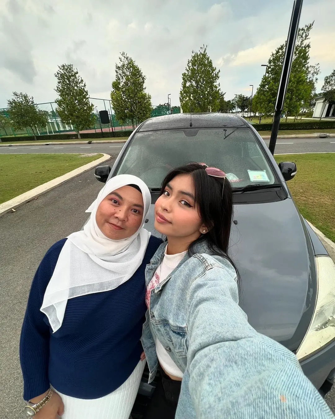 Qistina Raisah and her mom standing next to their exora car 