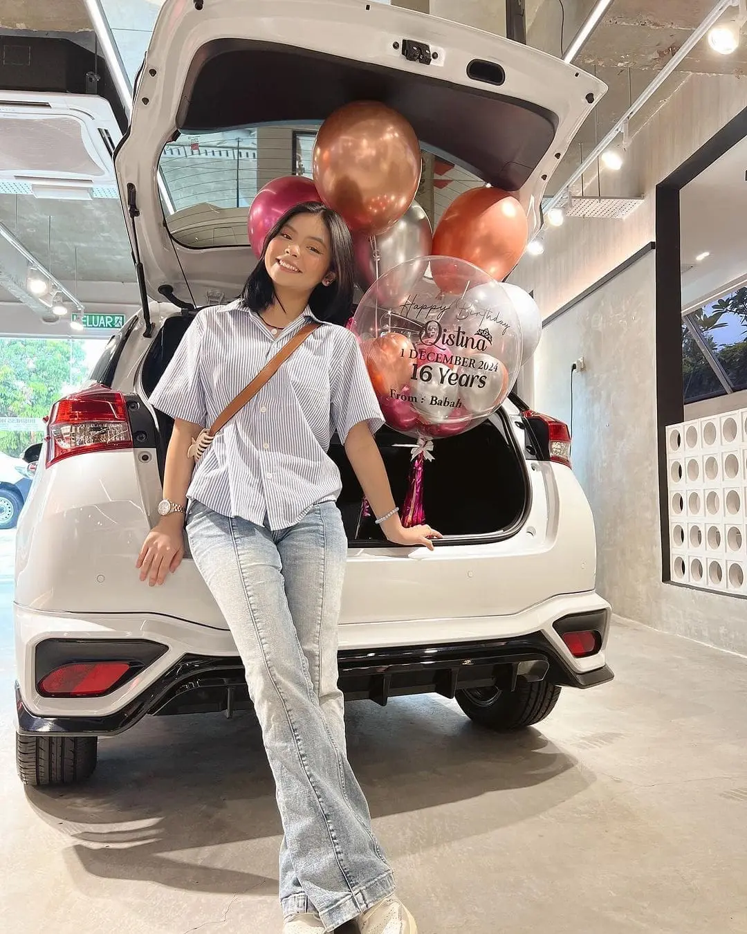Qistina Raisah standing next to her new car Toyota Yaris 