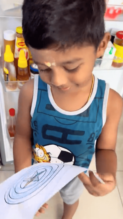 S. Vishvan Raaj showing his captain america shield's drawing to his parents