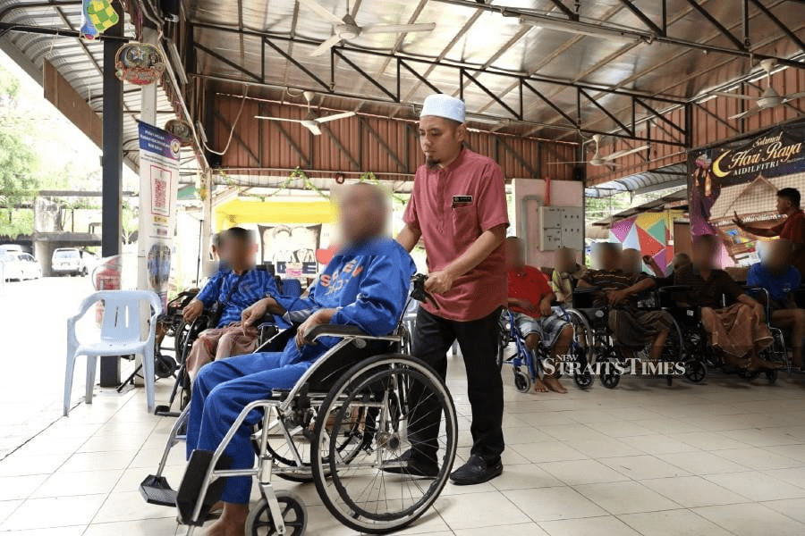 Saifullah pushing an old man on the wheelchair