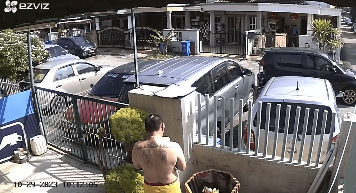 Msian man was watering a plant outside his house.