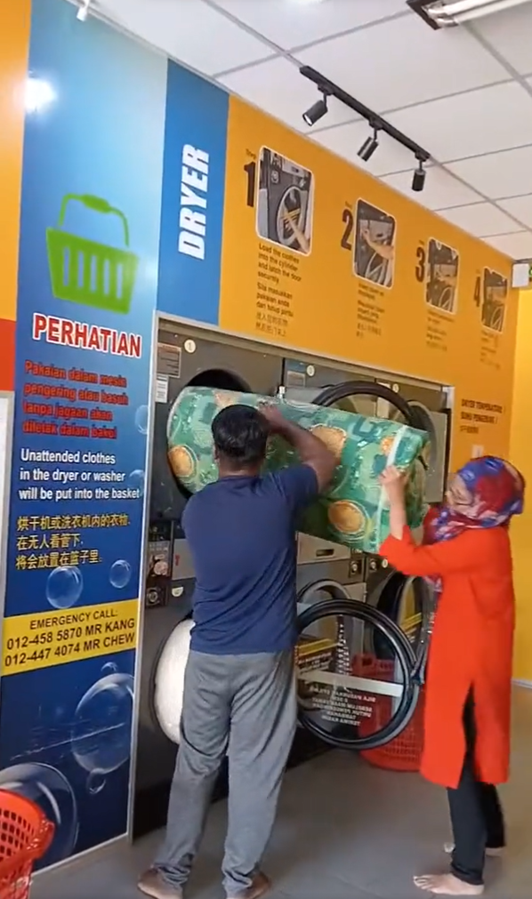 Couple putting mattress into dryer