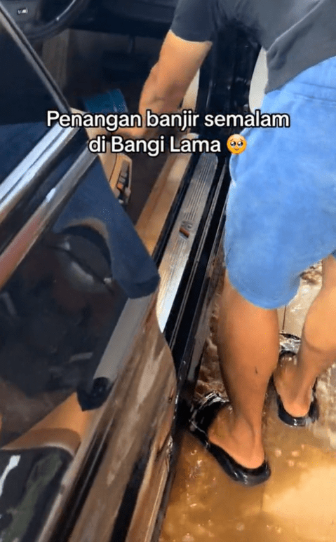 Man drains floodwater from BMW with a pail