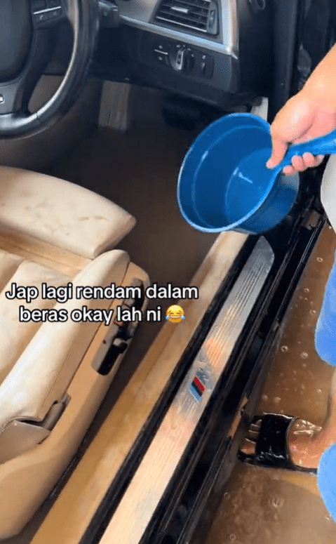 Man drains floodwater from BMW with a pail
