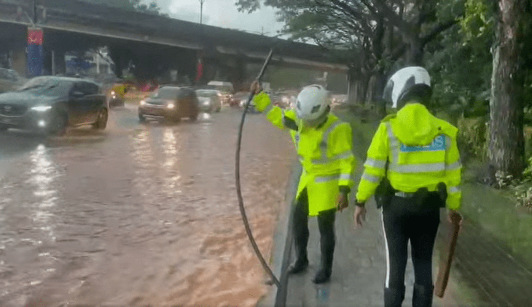 Traffic officers fixing clogged drain in JB with wooden stick