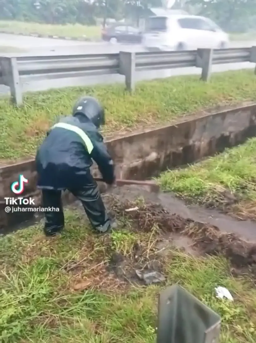 M'sian Man Drains Flooded Highway Road By Digging Pathway Under Heavy Rain