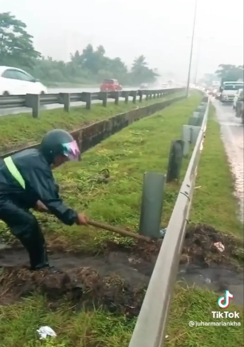 M'sian Man Drains Flooded Highway Road By Digging Pathway Under Heavy Rain