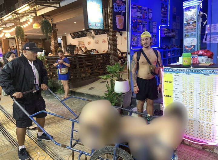 Thai policeman wheels drunk tourists back to hostel with pushcart