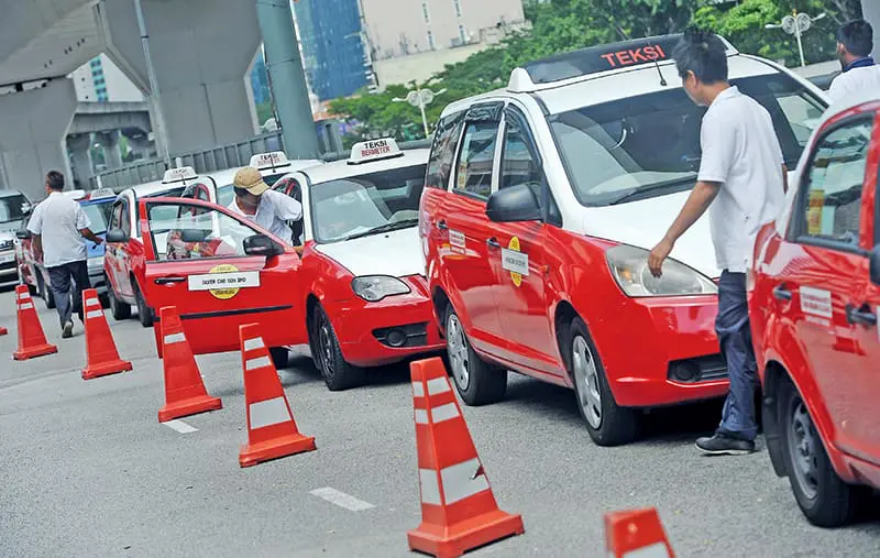 A group of taxi drivers parked their cars at the side of the road.