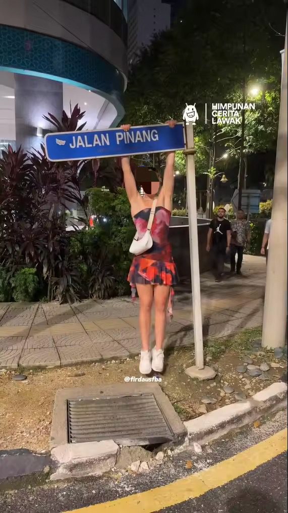 Tourist hangs off road sign 1
