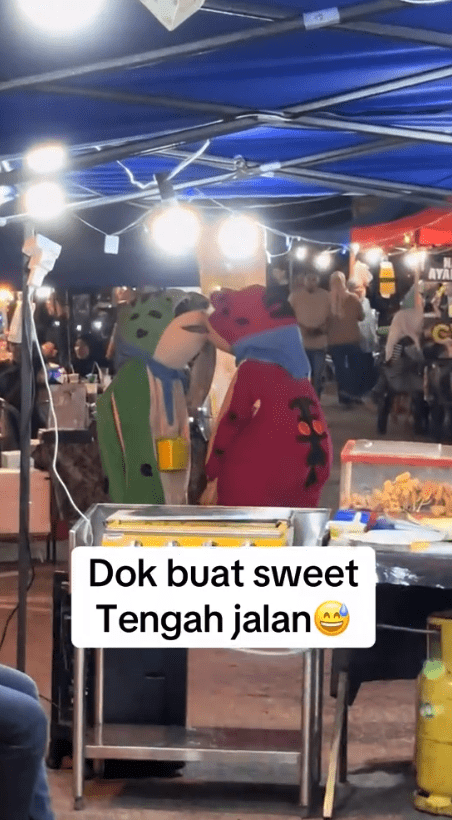 two frog mascots caught kissing