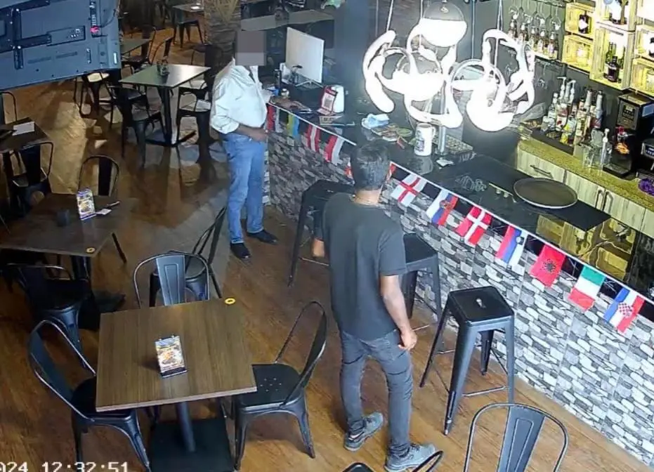 two men talking to the staff in a restaurant