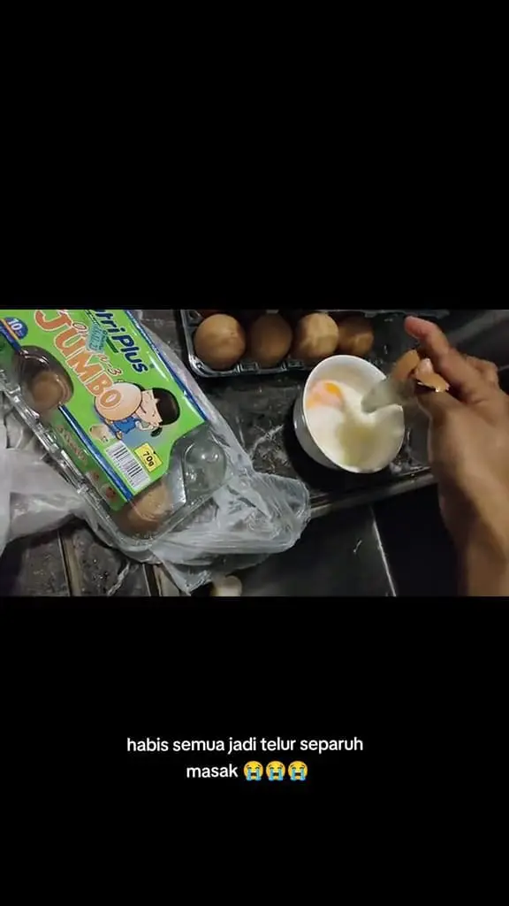 Msian woman cracking the half-cooked egg in a bowl