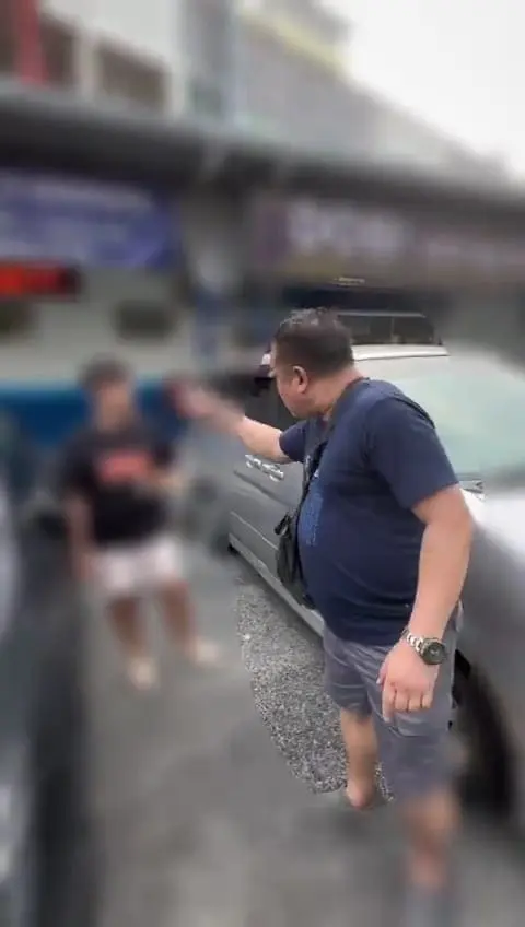 An angry Msian man scolding a male student for turning on his headlights