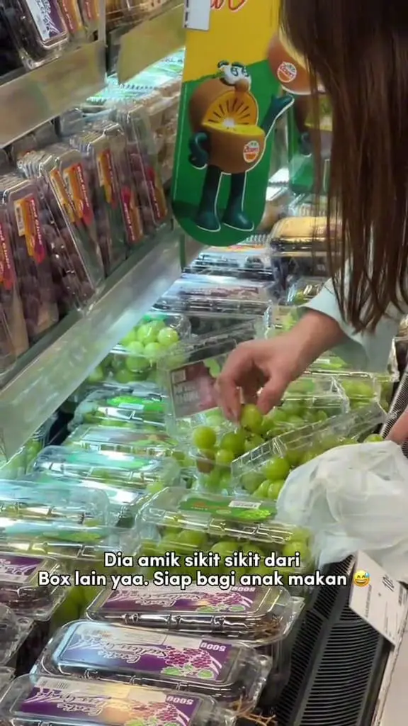 Malaysian woman switching grapes at mall and even give some to her son to eat