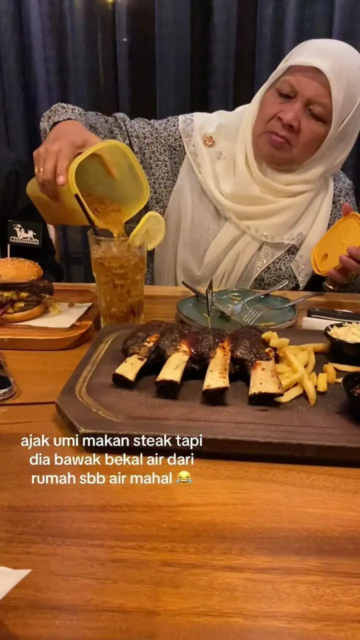 Msian mother pouring Teh O ice into a glass in a restaurant