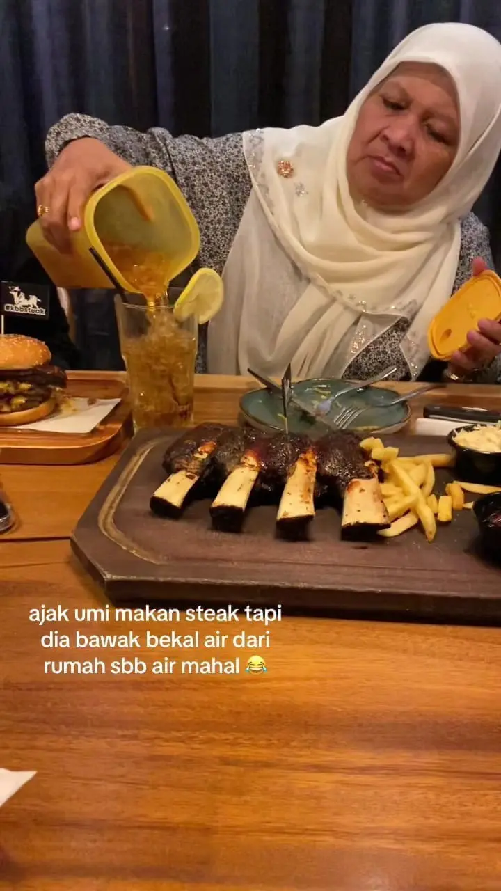 Msian mother pouring Teh O ice into a glass in a restaurant