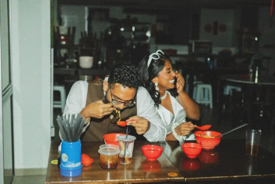 Priscilla giggling at her husband who is eating the Pan Mee.