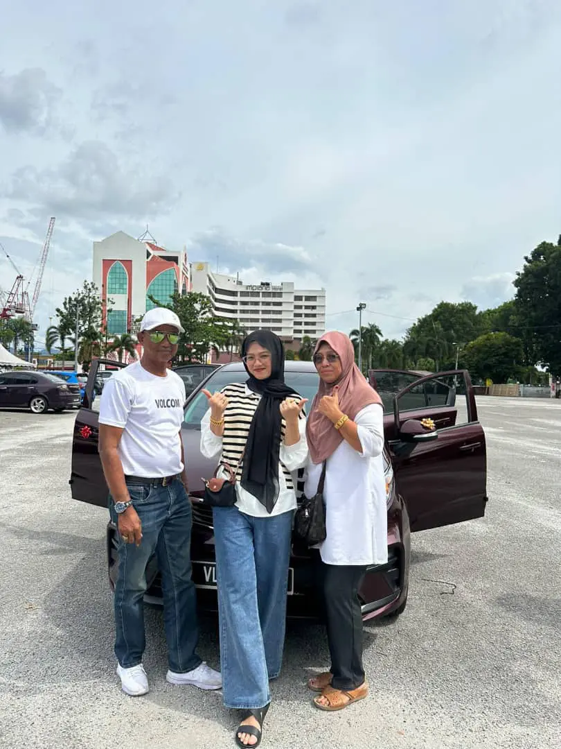 Msian woman with her parents standing in front of their new car, 
