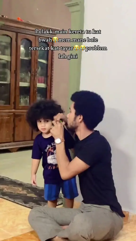 Msian father is trying to untangle the car that was stuck into his son's hair.