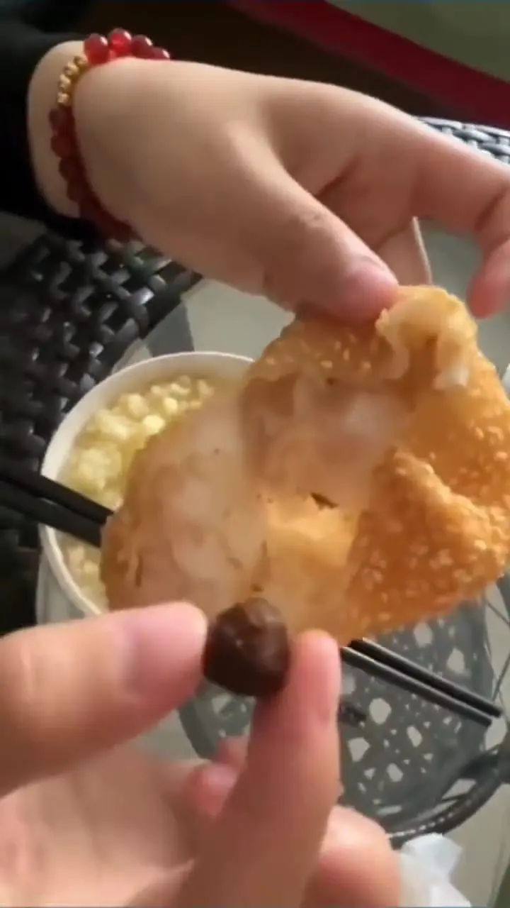Msian woman holding a pea sized of red bean filling inside the sesame ball.