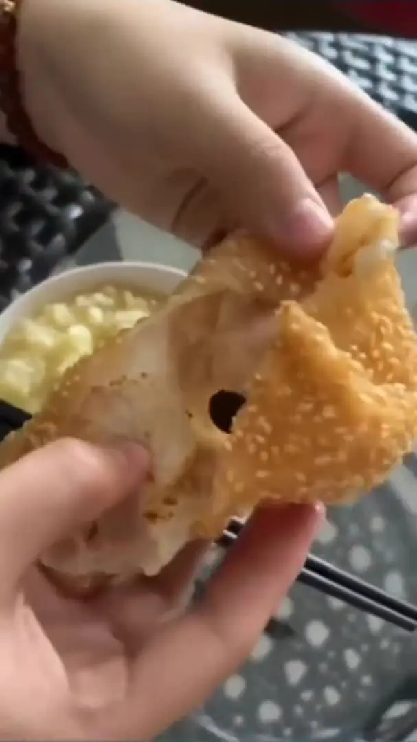 Msian woman showing a pea sized of red bean filling inside the sesame ball.