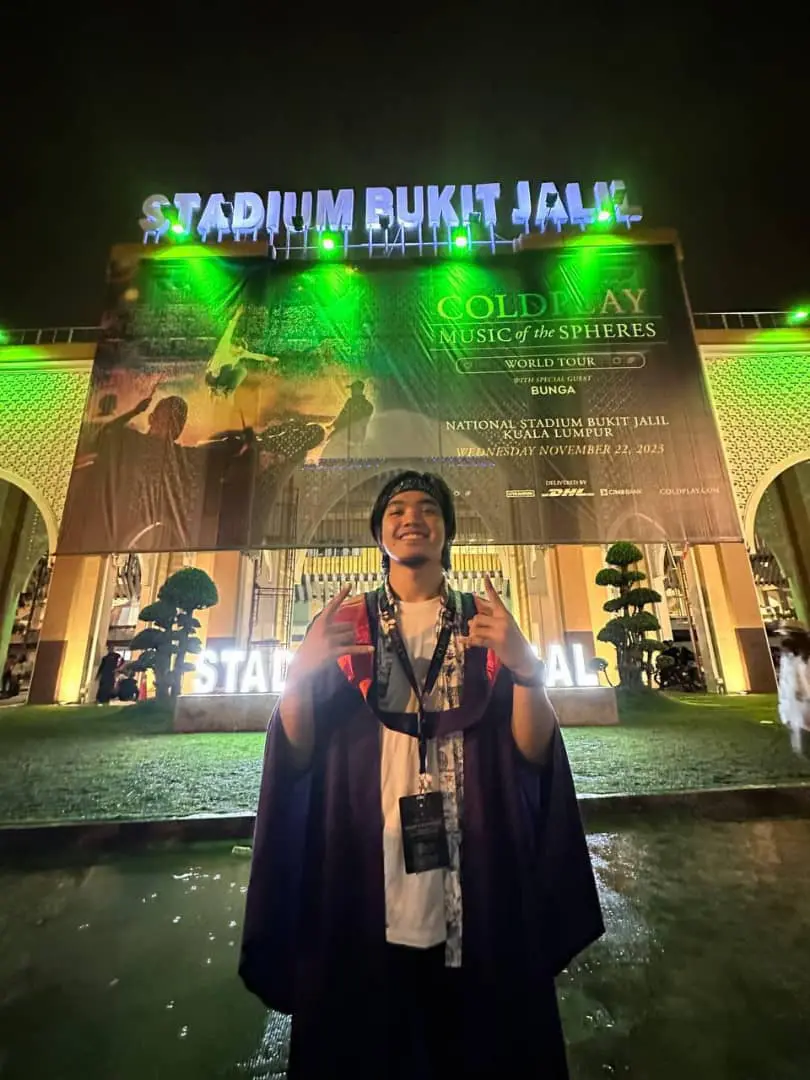 A USM graduate standing in front of the National Staidum after Coldplay's concert ends