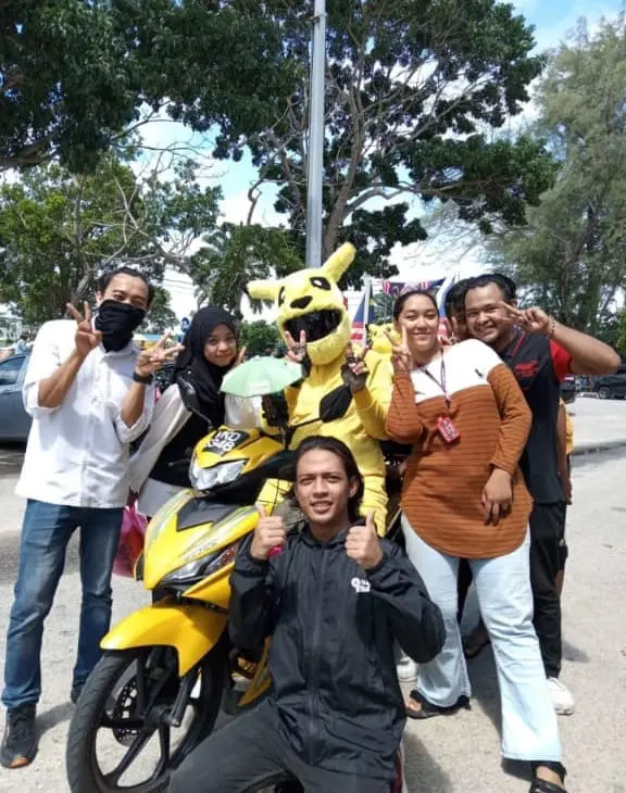 M'sian Grab Food Rider in Pikachu suit taking picture with people. 