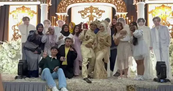 Msian couple and their friends taking a group picture with BTS standees on stage.
