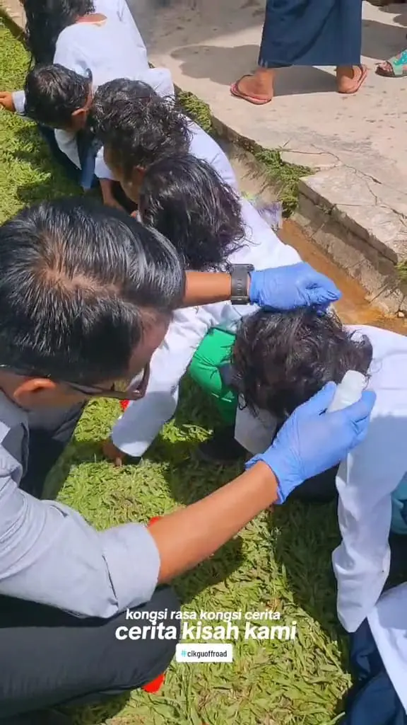 Msian teacher applying lice treatment serum to the kid's hair. 
