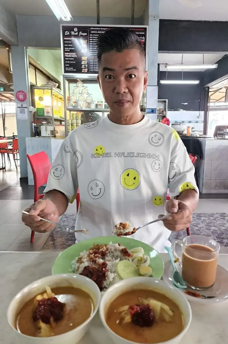 M'sian man eating nasi lemak at his favorite stall at Johor.