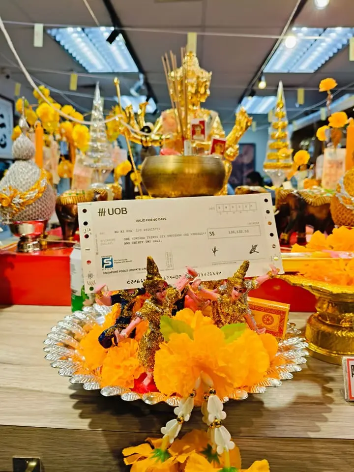 Winning cheque in front of shrine