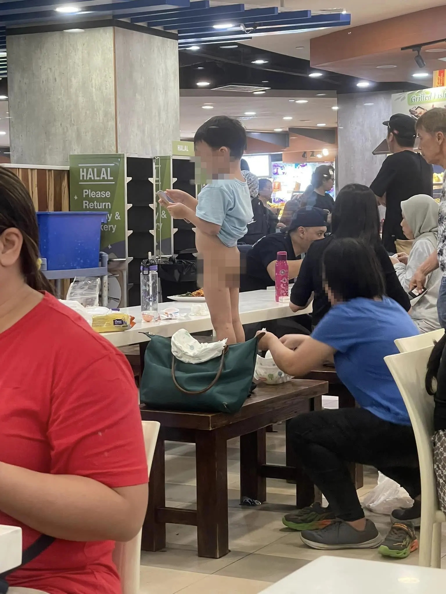 Woman changes son's diapers at SG food court