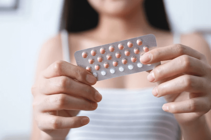 Woman holding birth control pills