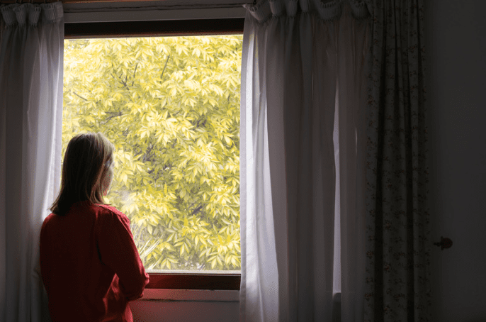 Woman looking out from room window