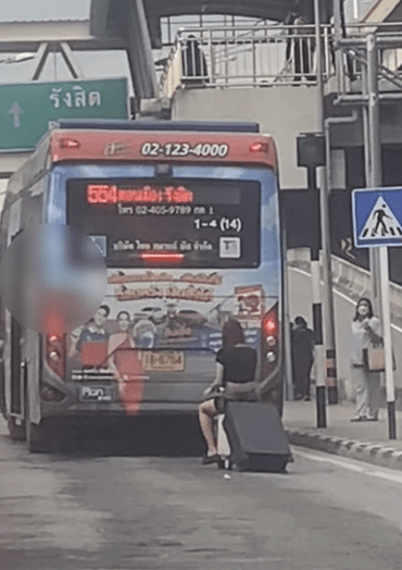 woman riding motorised luggage behind a bus
