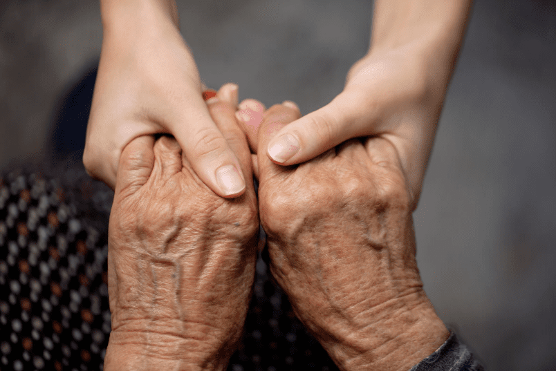 Young person holding old person's hands