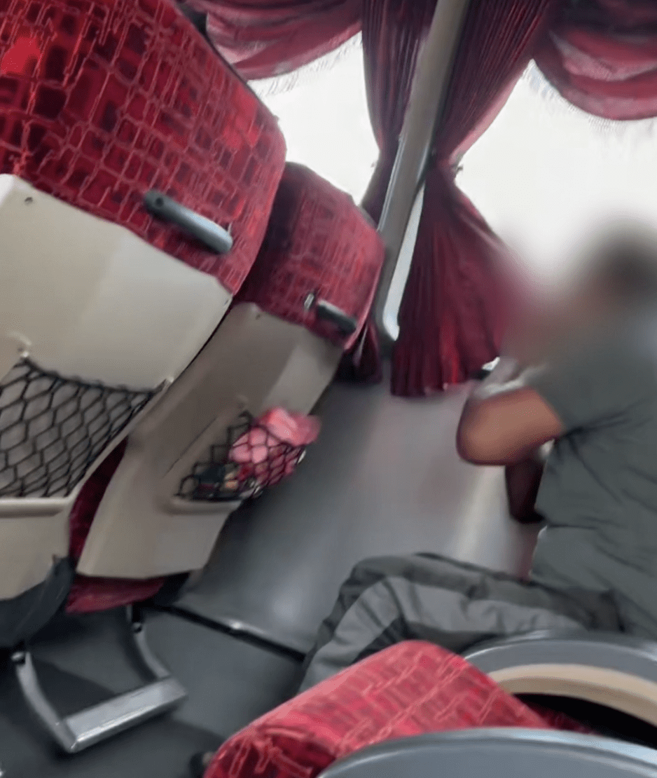 Passenger wiping mouth on bus curtain