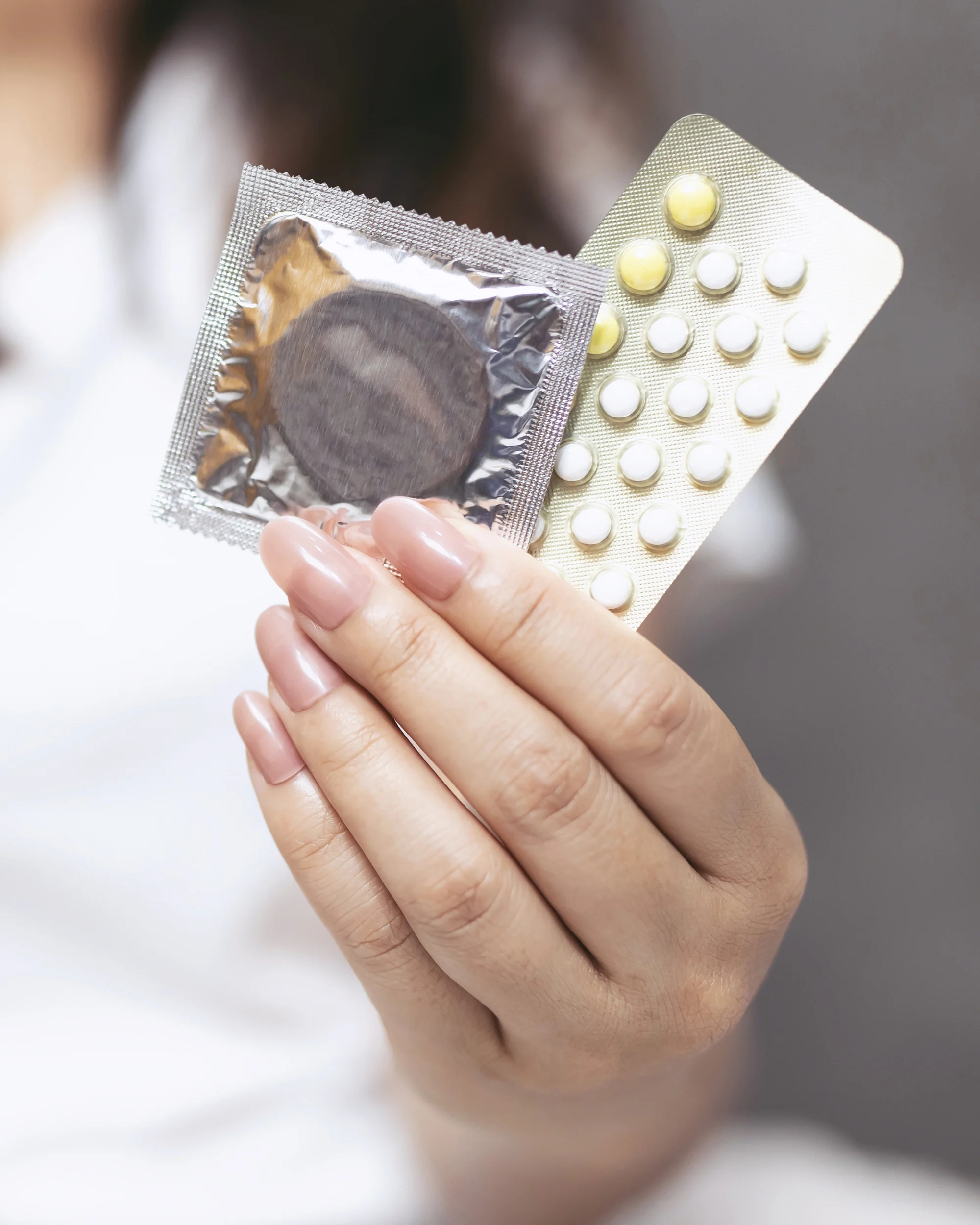A woman holding birth control and condoms