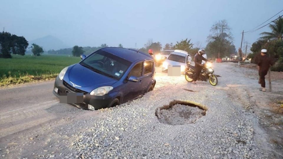 cars trapped in potholes in kedah road