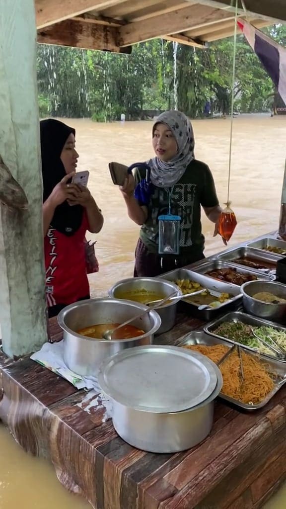 The customers patiently waiting in the floodwater while the seller packed their food.
