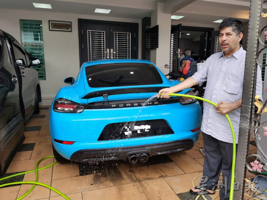 Datuk Amaluddin washing his porsche car that was damaged by the flood