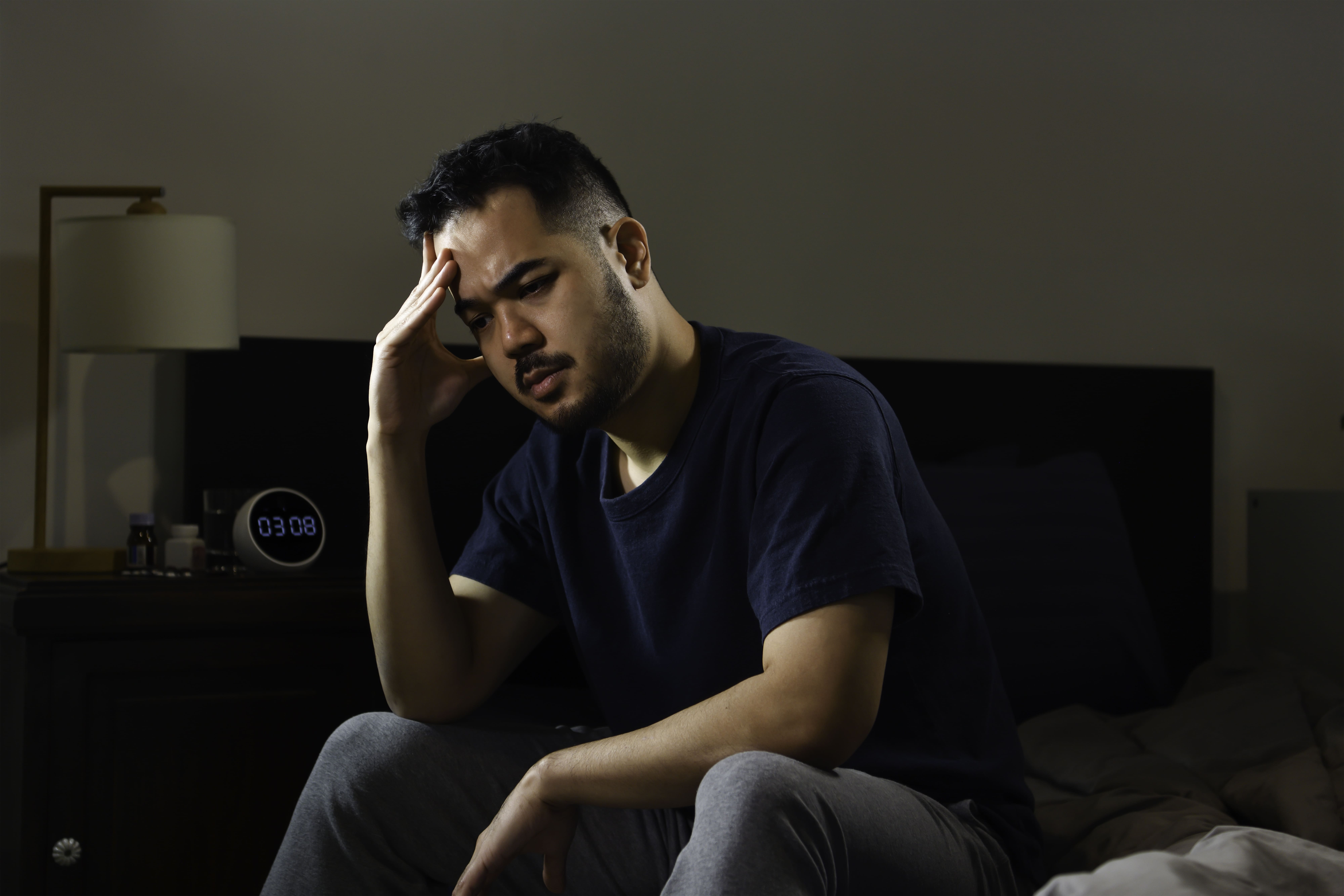 Depressed man sitting in bed. 