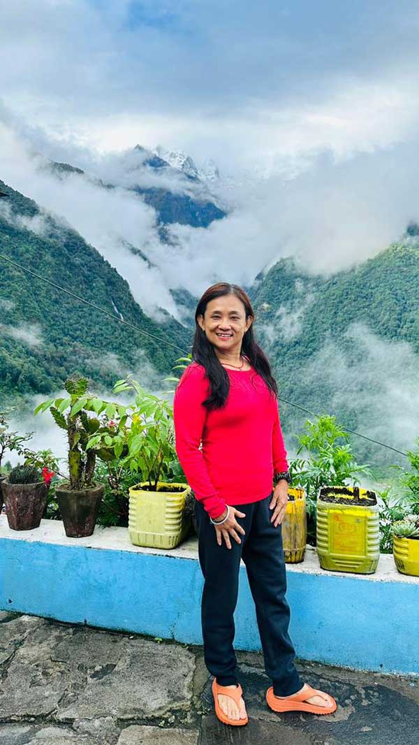 Zhang Ruixin is standing on a balcony with mountain scenery behind her.