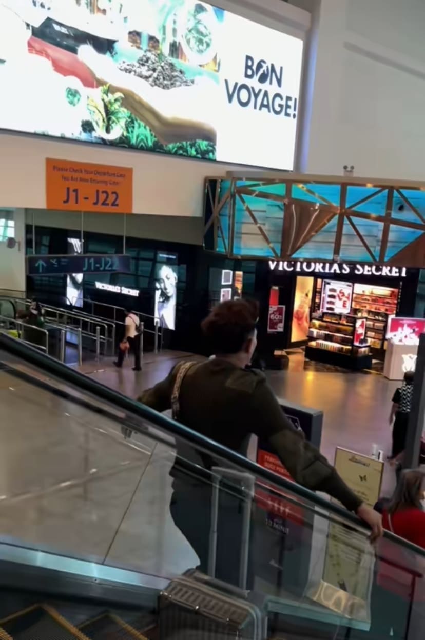 Man standing on escalator with luggage by his side in KLIA2 