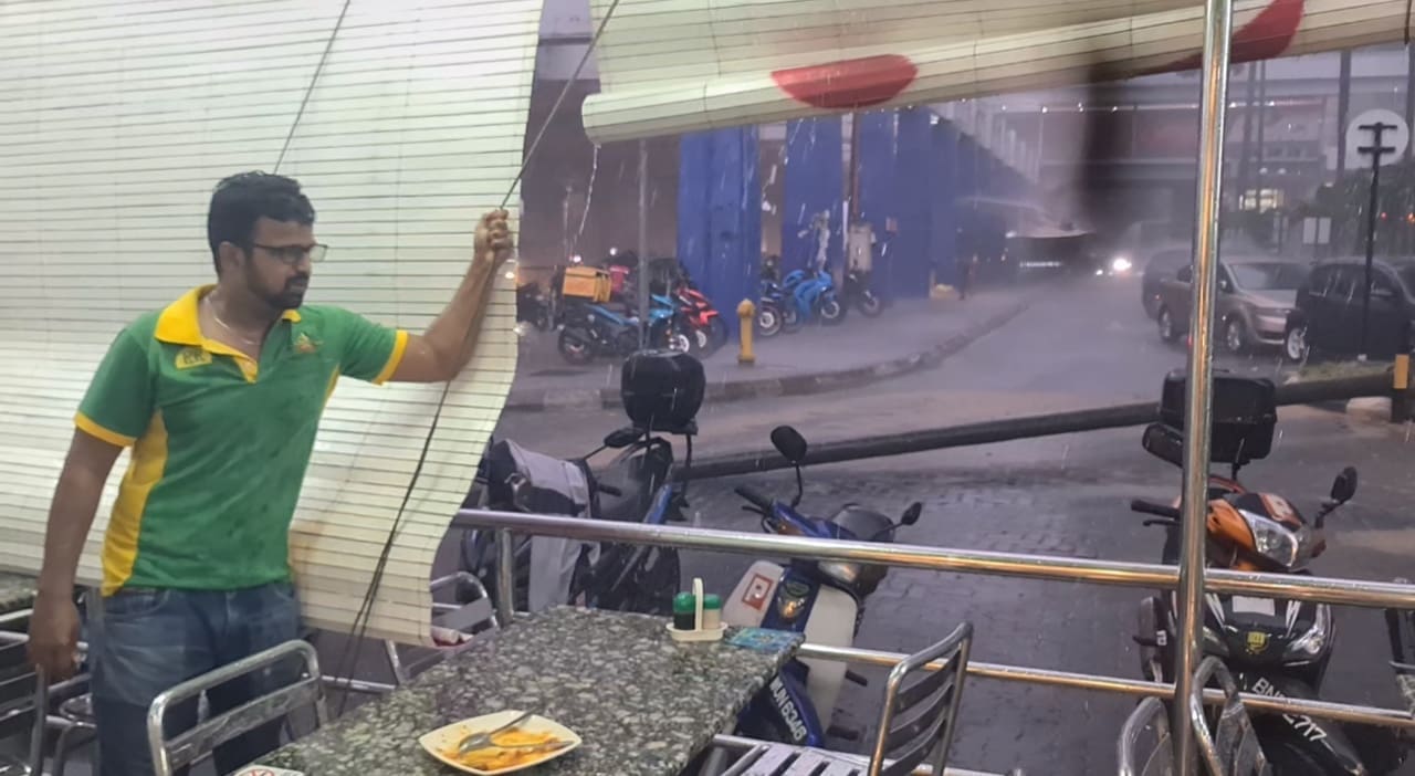 Nasi kandar worker holding the curtain to make sure the rain doesnt affect the customers 
