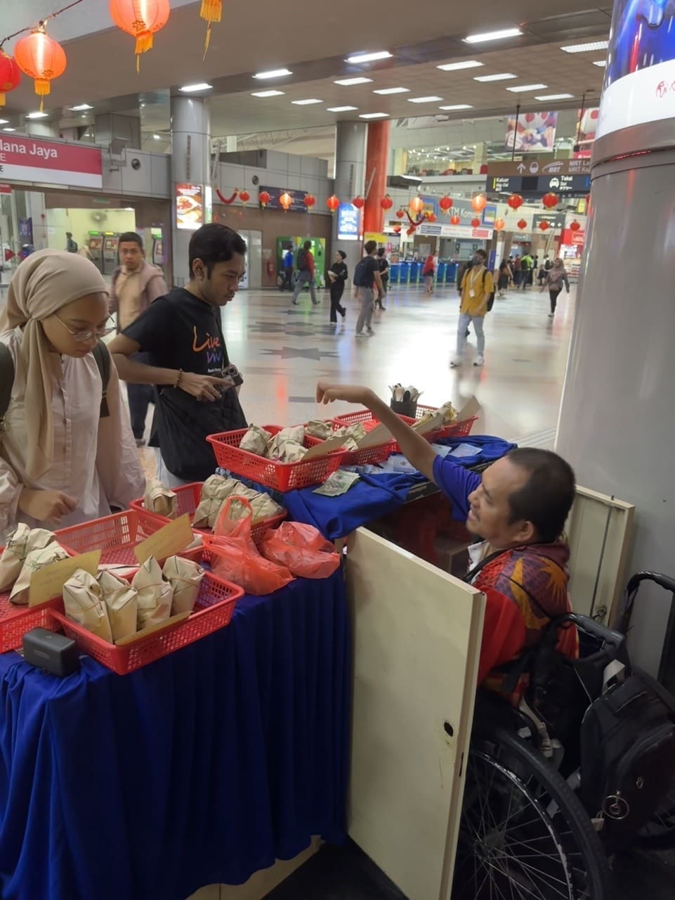 Mohd selling Nasi Lemak to customers in a wheelchair